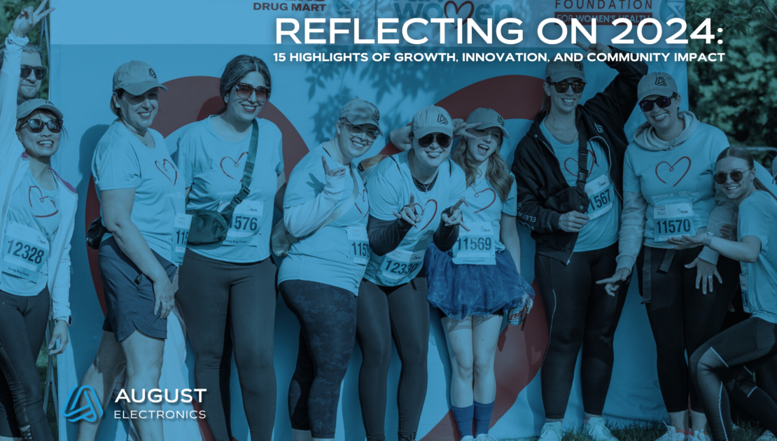 A group of August Electronics team members smiling and posing together at the Shoppers Drug Mart Run for Women event in 2024. The group is wearing matching blue shirts with a heart design, celebrating community involvement and teamwork. The backdrop features the event branding and logos, with the headline text "Reflecting on 2024: 15 Highlights of Growth, Innovation, and Community Impact" overlaid.